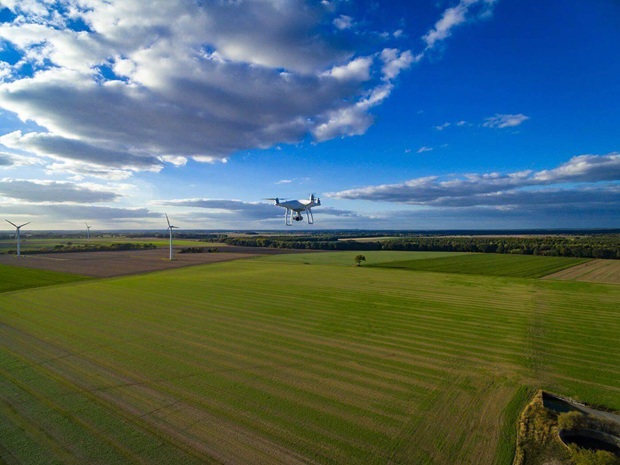 Drohne im Flug über Feldern und Windkraftanlagen