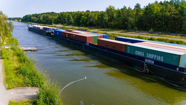 Professionelle Drohnenaufnahme eines beladenen Containerschiffs auf einer Binnenwasserstraße zur Visualisierung von Logistikketten.