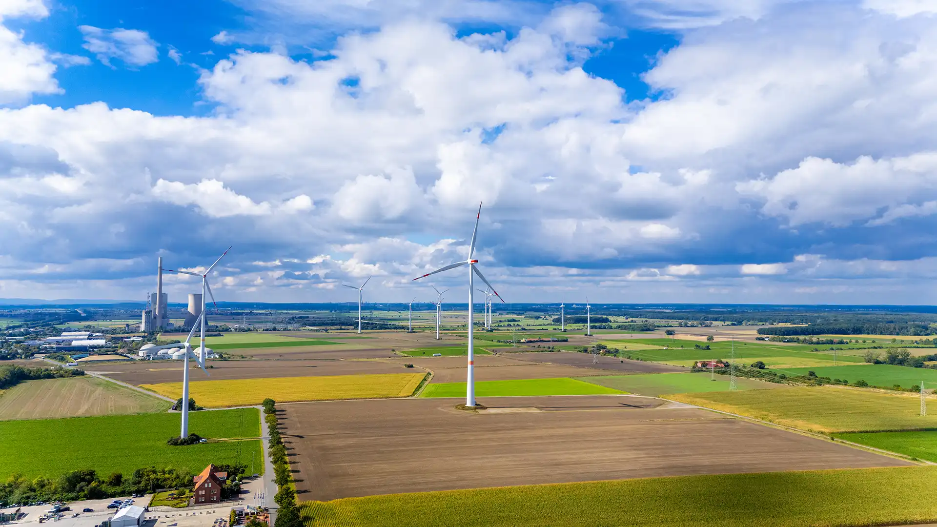 Übersichtsaufnahme eines Windparks mit mehreren Windkraftanlagen in einer Agrarlandschaft