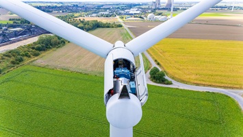 Professionelle Drohnen-Inspektion einer Windkraftanlage zur Überprüfung von Rotorblättern und Turm auf Schäden.