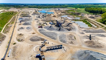 Professioneller Drohnenflug über das Gelände einer Kiesgrube zur Standortvisualisierung.